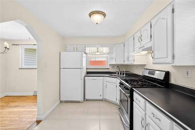 228 Mcmasters Dr, Monroeville, PA 15146 - kitchen featuring white appliances, under cabinet range hood, dark countertops, white cabinetry, and arched walkways