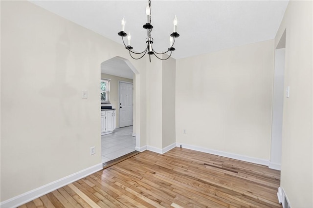 228 Mcmasters Dr, Monroeville, PA 15146 - empty room featuring arched walkways, light wood-type flooring, and a chandelier