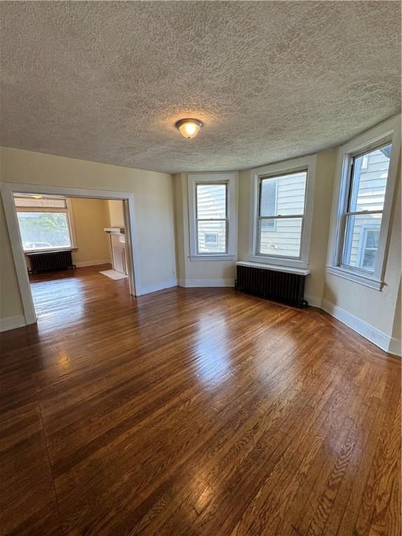 207 N Sprague Ave, Bellevue, PA 15202 - empty room featuring radiator heating unit, a textured ceiling, and dark wood-style flooring