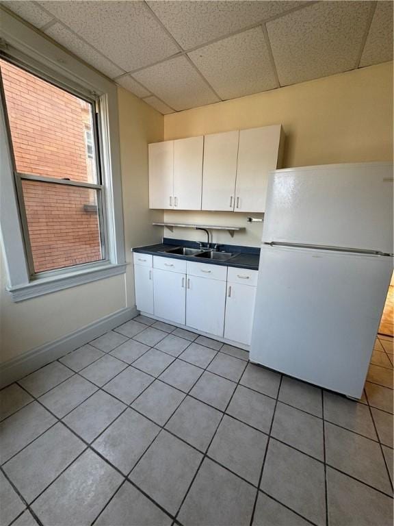 207 N Sprague Ave, Bellevue, PA 15202 - kitchen with freestanding refrigerator, dark countertops, white cabinets, light tile patterned flooring, and a drop ceiling