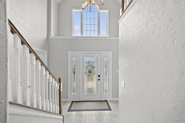 1007 Cicero Dr, Hempfield Twp, PA 15642 - tiled entryway featuring a textured wall, stairway, high vaulted ceiling, and a chandelier