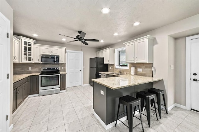 1007 Cicero Dr, Hempfield Twp, PA 15642 - kitchen with appliances with stainless steel finishes, a peninsula, white cabinets, decorative backsplash, and recessed lighting