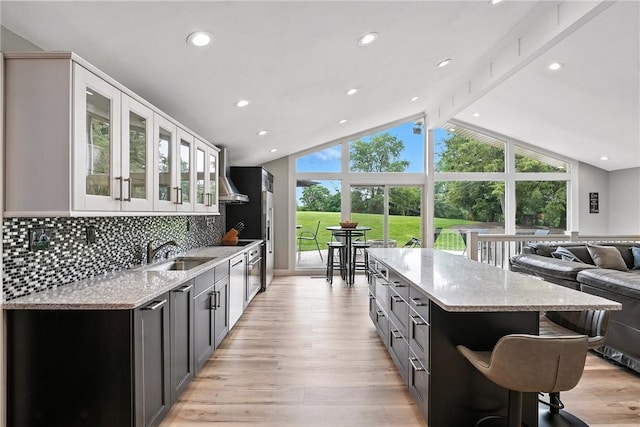 251 Myers Ln, Indiana Twp, PA 15101 - kitchen with a center island, lofted ceiling, wall chimney range hood, light stone counters, and glass insert cabinets