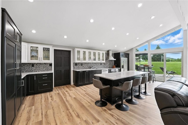 251 Myers Ln, Indiana Twp, PA 15101 - kitchen featuring wall chimney exhaust hood, backsplash, white cabinets, a breakfast bar area, and glass insert cabinets