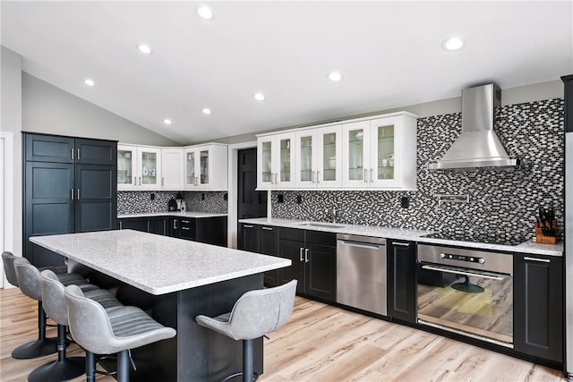 251 Myers Ln, Indiana Twp, PA 15101 - kitchen featuring wall chimney range hood, stainless steel appliances, decorative backsplash, dark cabinetry, and vaulted ceiling