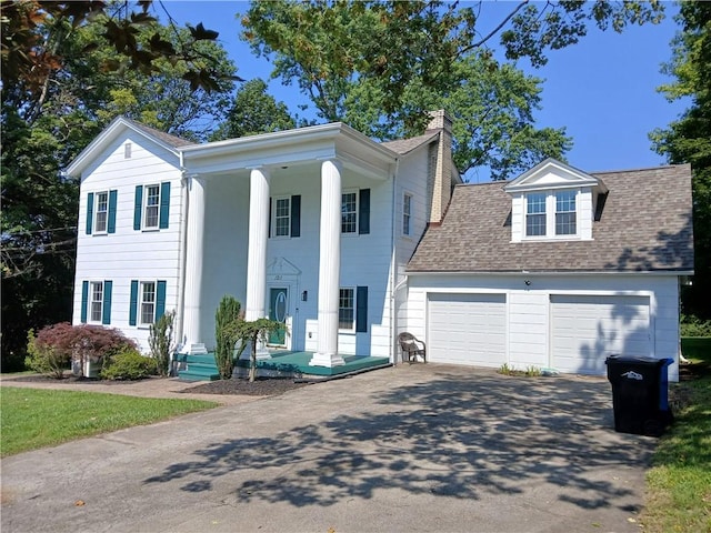 1211 Reed St, North Huntingdon, PA 15642 - neoclassical home featuring driveway, a chimney, a garage, roof with shingles, and covered porch