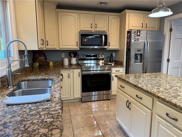 293 Sandy Hill Rd, Middlesex Twp, PA 16059 - kitchen featuring stainless steel appliances, dark stone counters, decorative light fixtures, cream cabinetry, and light tile patterned flooring