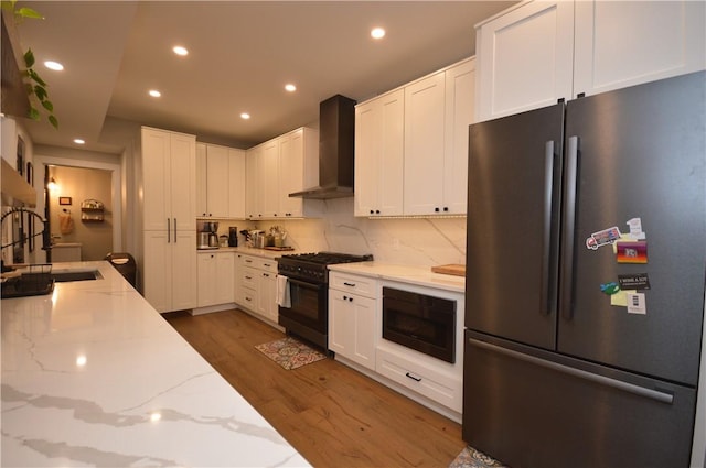 710 Cedar Ave, Central North Side, PA 15212 - kitchen with freestanding refrigerator, black range with gas stovetop, wall chimney exhaust hood, built in microwave, and wood finished floors