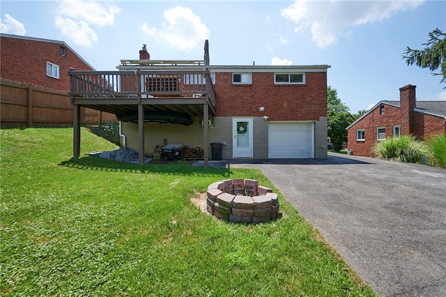1023 Bellair Rd, Port Vue, PA 15133 - rear view of house featuring asphalt driveway, an outdoor fire pit, a wooden deck, a garage, and a lawn