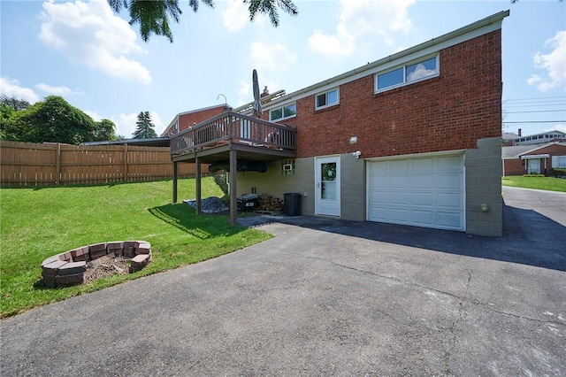 1023 Bellair Rd, Port Vue, PA 15133 - back of house with an attached garage, driveway, a wooden deck, a fire pit, and brick siding