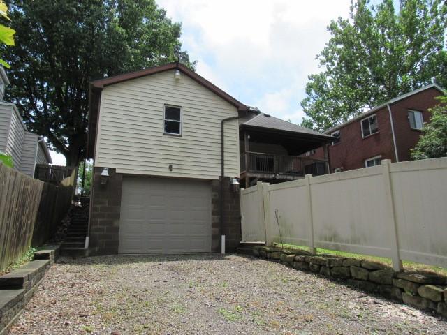 409 Keystone Dr, New Kensington, PA 15068 - rear view of house with a garage, gravel driveway, and stairway