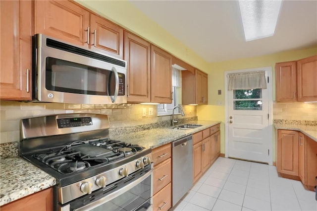 7034 Penn Ave, Point Breeze, PA 15208 - kitchen with appliances with stainless steel finishes, decorative backsplash, light stone countertops, light tile patterned floors, and brown cabinets