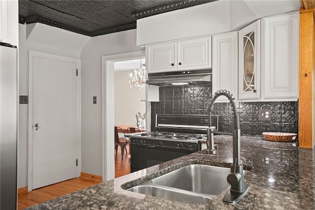 1302 Mount Royal Blvd, Shaler, PA 15223 - kitchen featuring under cabinet range hood, white cabinetry, tasteful backsplash, light wood finished floors, and dark stone countertops
