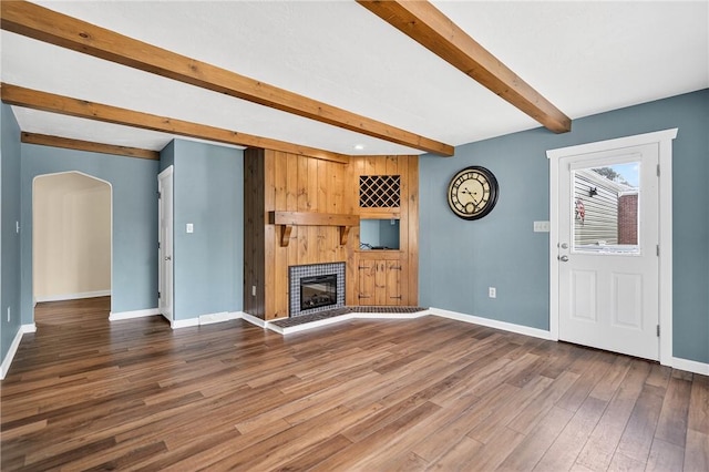 112 Oxford Pl, Saint Clair, PA 15241 - unfurnished living room featuring beamed ceiling, a fireplace with raised hearth, wood finished floors, arched walkways, and recessed lighting