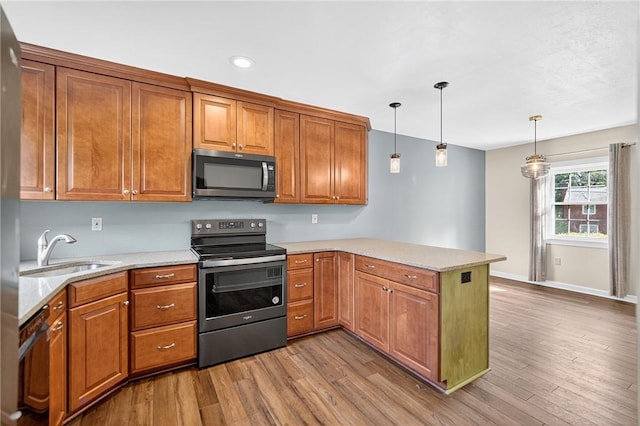 112 Oxford Pl, Saint Clair, PA 15241 - kitchen featuring appliances with stainless steel finishes, a peninsula, brown cabinetry, wood finished floors, and recessed lighting