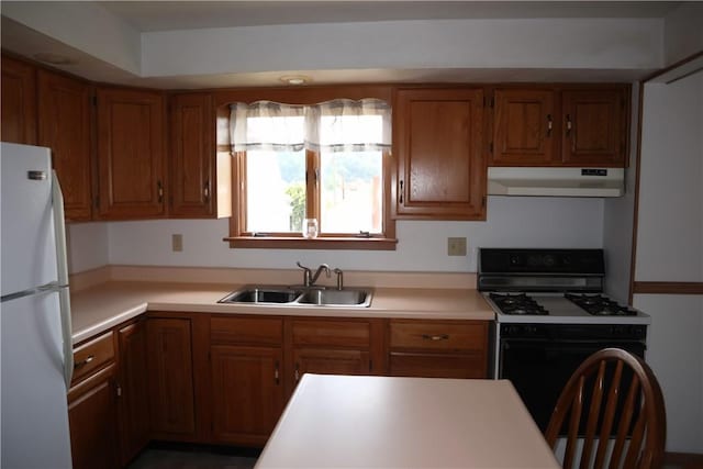 721 Spring St, Roscoe, PA 15477 - kitchen featuring freestanding refrigerator, under cabinet range hood, gas range, brown cabinets, and light countertops
