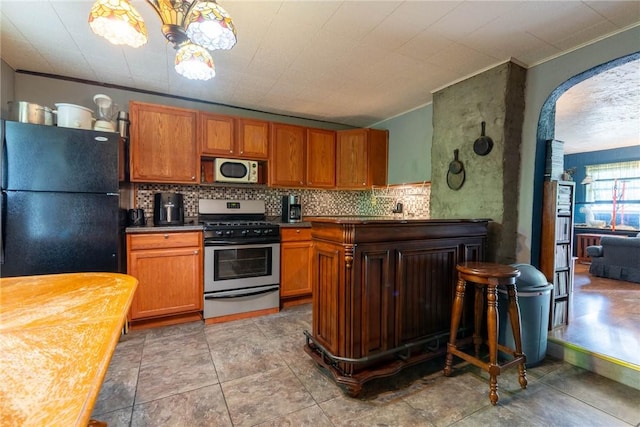 309 Francis Ave, Monongahela, PA 15063 - kitchen with appliances with stainless steel finishes, arched walkways, dark countertops, decorative backsplash, and brown cabinets