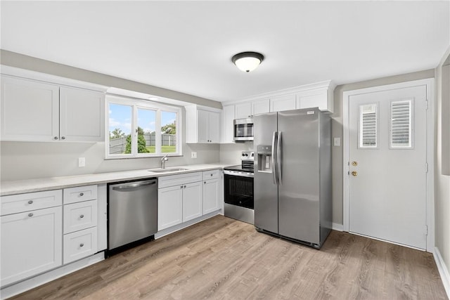 88 Pennsylvania Blvd, Monessen, PA 15062 - kitchen featuring appliances with stainless steel finishes, white cabinetry, light wood-style flooring, and light countertops