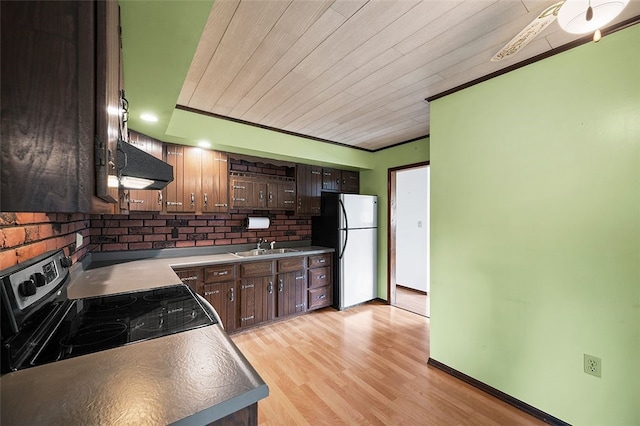 115 Shippingport Rd, Aliquippa, PA 15001 - kitchen featuring freestanding refrigerator, wall chimney range hood, dark brown cabinets, light wood-style floors, and ornamental molding