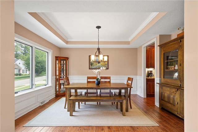 207 Tamarack Dr, Adams Twp, PA 16046 - dining room with a tray ceiling, a chandelier, hardwood / wood-style flooring, ornamental molding, and wainscoting