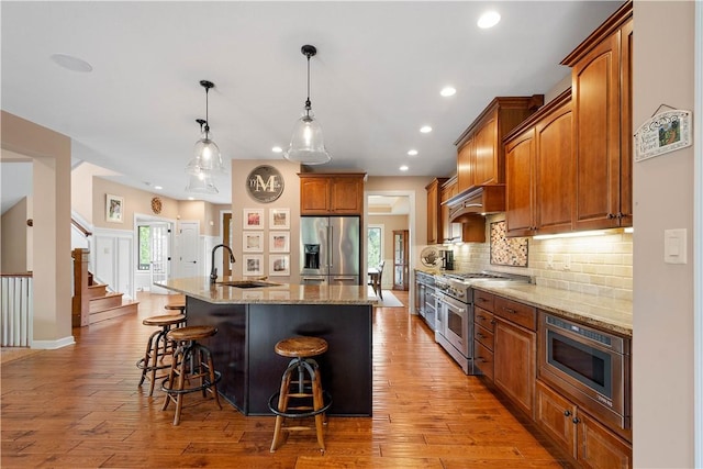 207 Tamarack Dr, Adams Twp, PA 16046 - kitchen with stainless steel appliances, light stone counters, tasteful backsplash, a center island with sink, and a kitchen breakfast bar