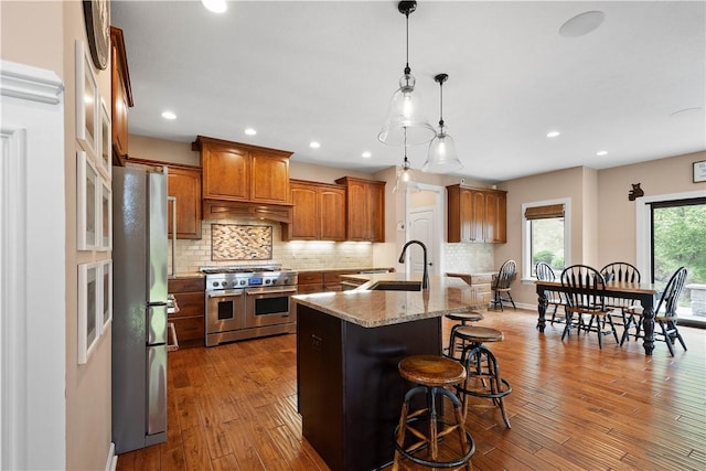 207 Tamarack Dr, Adams Twp, PA 16046 - kitchen featuring stainless steel appliances, a kitchen breakfast bar, a center island with sink, dark wood finished floors, and backsplash