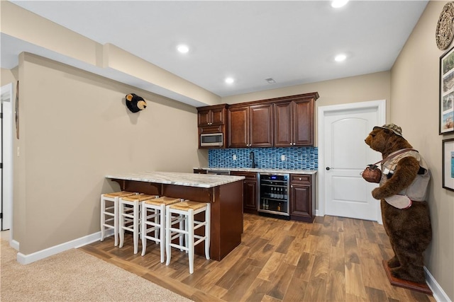 207 Tamarack Dr, Adams Twp, PA 16046 - kitchen featuring beverage cooler, stainless steel microwave, a breakfast bar area, dark brown cabinets, and a peninsula