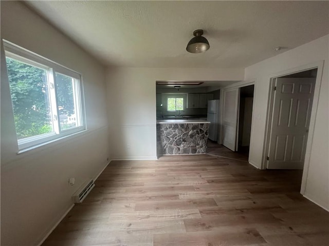 1735 Kimball Ave, New Kensington, PA 15068 - unfurnished dining area with a baseboard heating unit, healthy amount of natural light, and light wood-style flooring