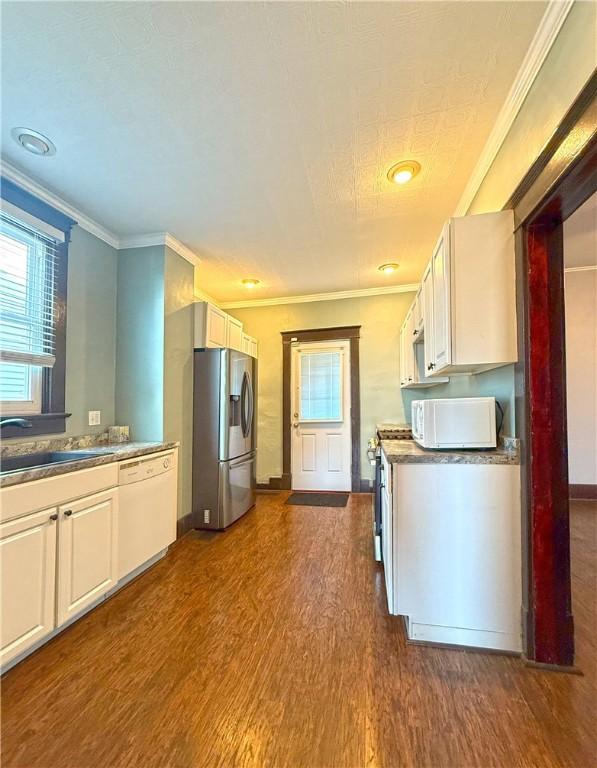 514 Linden Ave, New Kensington, PA 15068 - kitchen with white appliances, dark wood-style flooring, ornamental molding, and white cabinetry