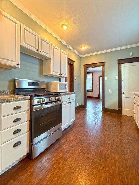 514 Linden Ave, New Kensington, PA 15068 - kitchen featuring stainless steel range with gas cooktop, dark wood-style flooring, crown molding, white microwave, and white cabinets