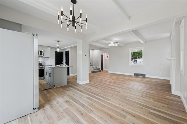 327 Charles Ave, New Kensington, PA 15068 - unfurnished living room featuring arched walkways, a chandelier, light wood-style floors, beamed ceiling, and stairway