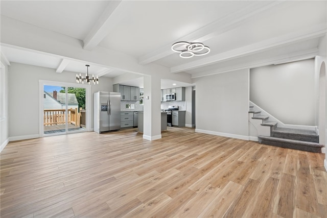 327 Charles Ave, New Kensington, PA 15068 - unfurnished living room featuring a chandelier, light wood finished floors, beamed ceiling, and stairs