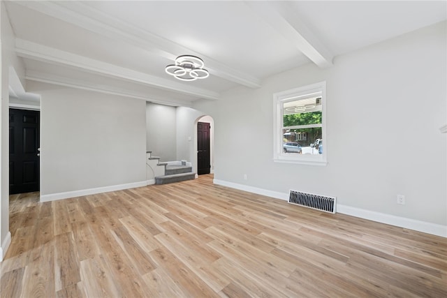 327 Charles Ave, New Kensington, PA 15068 - unfurnished living room featuring arched walkways, beamed ceiling, stairs, and light wood-style floors