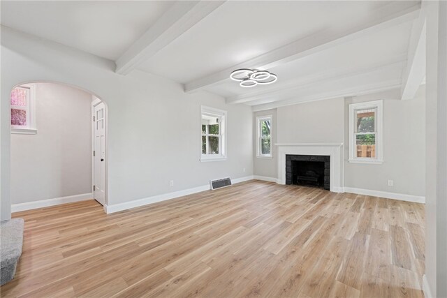 327 Charles Ave, New Kensington, PA 15068 - unfurnished living room with healthy amount of natural light, light wood-style floors, arched walkways, beamed ceiling, and a fireplace