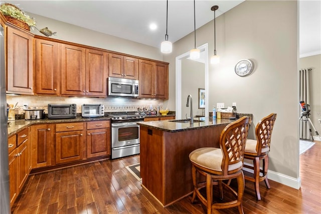 1 Riverfront St, Oakmont, PA 15139 - kitchen featuring stainless steel appliances, dark wood finished floors, brown cabinets, and a peninsula