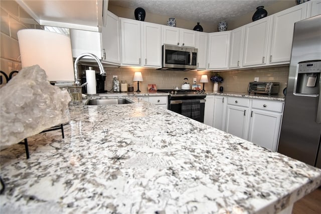 121 Sedeca Dr, North Strabane, PA 15317 - kitchen with stainless steel appliances, white cabinets, tasteful backsplash, light stone counters, and a textured ceiling