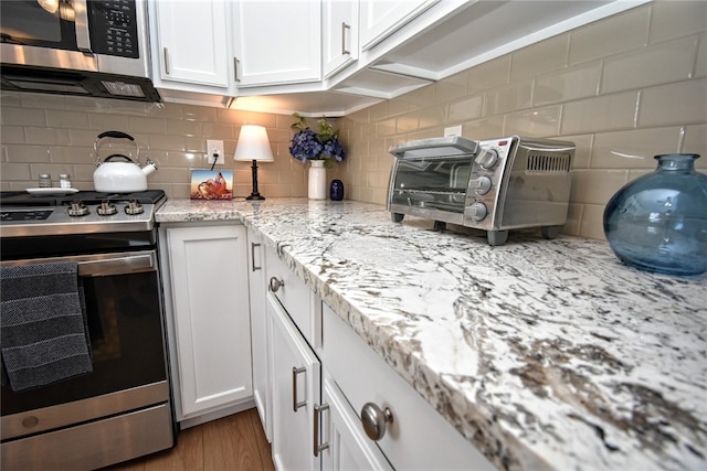 121 Sedeca Dr, North Strabane, PA 15317 - kitchen with stainless steel appliances, backsplash, white cabinets, light stone countertops, and wood finished floors