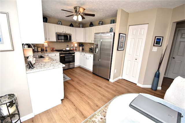 121 Sedeca Dr, North Strabane, PA 15317 - kitchen with stainless steel appliances, light stone countertops, light wood finished floors, a ceiling fan, and white cabinetry