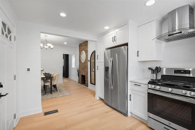 5110 Duncan St, Lawrenceville, PA 15201 - kitchen featuring appliances with stainless steel finishes, wall chimney range hood, light wood finished floors, white cabinetry, and recessed lighting