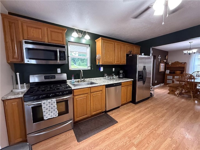 180 Beale Rd, Buffalo Twp, PA 16055 - kitchen with appliances with stainless steel finishes, light wood-style flooring, a textured ceiling, a chandelier, and brown cabinets