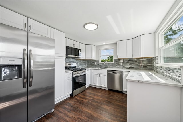 1611 Guffey Rd, North Huntingdon, PA 15642 - kitchen featuring appliances with stainless steel finishes, decorative backsplash, dark wood-style floors, light stone countertops, and white cabinetry