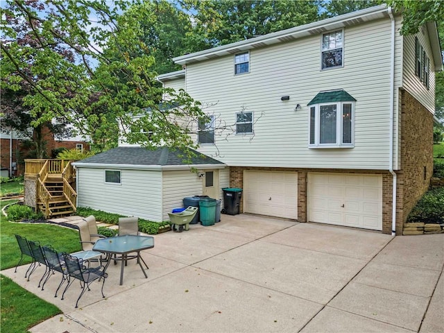 44 Stonehenge Dr, South Strabane, PA 15301 - back of house featuring brick siding, a garage, stairs, and driveway