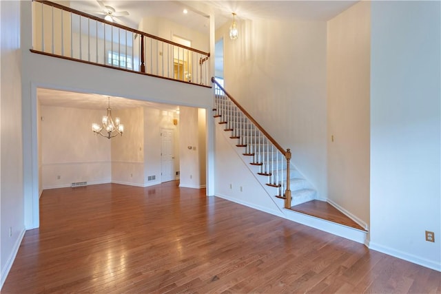 103 Boxwood Ct, Peters Twp, PA 15317 - unfurnished living room featuring stairs, a chandelier, wood finished floors, a ceiling fan, and a high ceiling