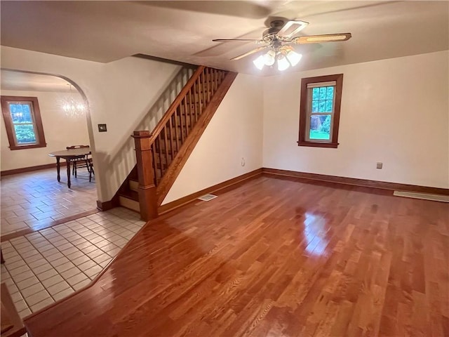 423 Bonniebrook Rd, Summit Twp, PA 16002 - unfurnished living room featuring arched walkways, stairway, ceiling fan, and wood finished floors