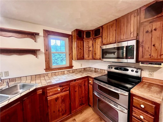 423 Bonniebrook Rd, Summit Twp, PA 16002 - kitchen featuring stainless steel appliances, open shelves, brown cabinetry, tile countertops, and light wood finished floors