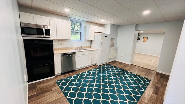 324 Paul Dr, Lower Burrell, PA 15068 - kitchen featuring stainless steel appliances, white cabinetry, light countertops, dark wood-type flooring, and a paneled ceiling
