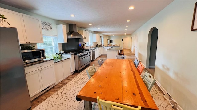 324 Paul Dr, Lower Burrell, PA 15068 - kitchen with wall chimney exhaust hood, stainless steel appliances, recessed lighting, a peninsula, and white cabinets