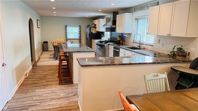 324 Paul Dr, Lower Burrell, PA 15068 - kitchen featuring wall chimney exhaust hood, stainless steel appliances, dark stone countertops, backsplash, and recessed lighting