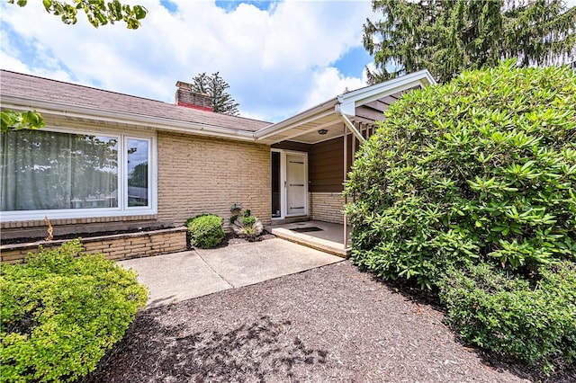 127 Mount Odin Dr, Hempfield Twp, PA 15601 - view of exterior entry featuring a chimney and brick siding