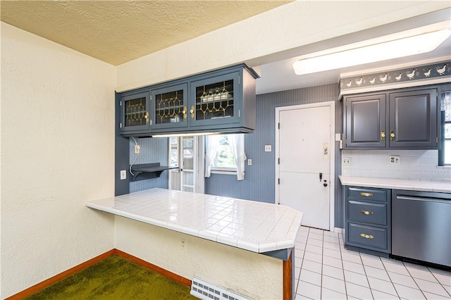 127 Mount Odin Dr, Hempfield Twp, PA 15601 - kitchen with stainless steel dishwasher, tile counters, a peninsula, glass insert cabinets, and healthy amount of natural light